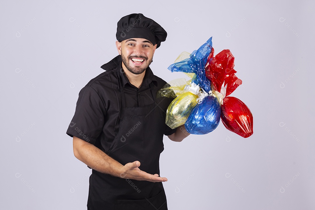 Homem jovem cozinheiro sobre fundo isolado segurando ovos de páscoa