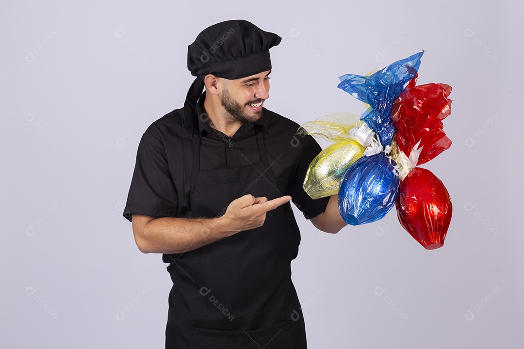 Homem jovem cozinheiro sobre fundo isolado segurando ovos de páscoa