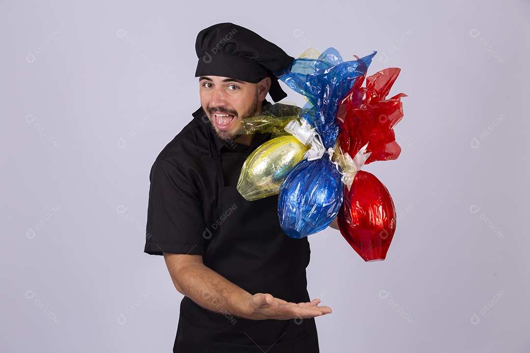 Homem jovem cozinheiro sobre fundo isolado segurando ovos de páscoa