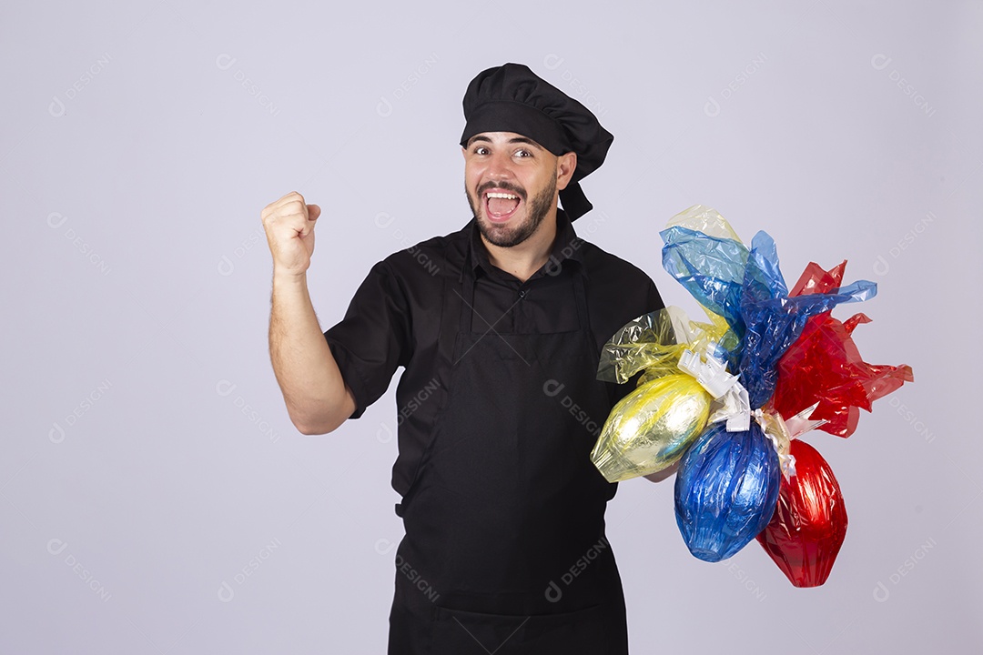Homem jovem cozinheiro sobre fundo isolado segurando ovos de páscoa