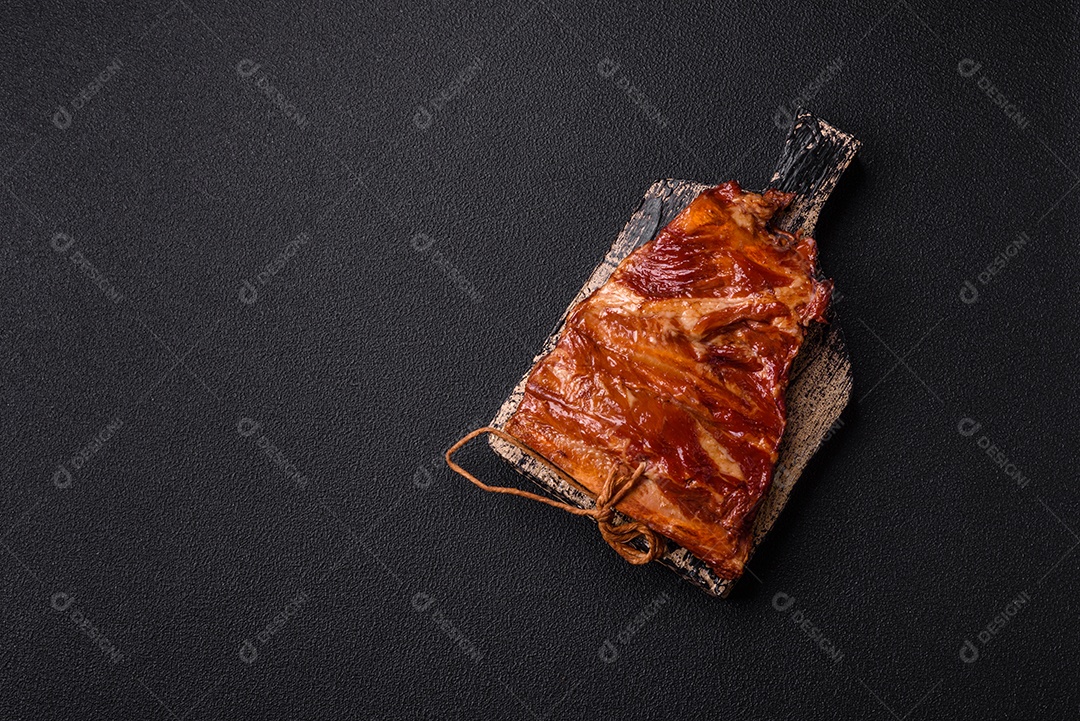 Deliciosas costelas defumadas ou grelhadas com azeitonas, especiarias e ervas sobre fundo escuro de concreto