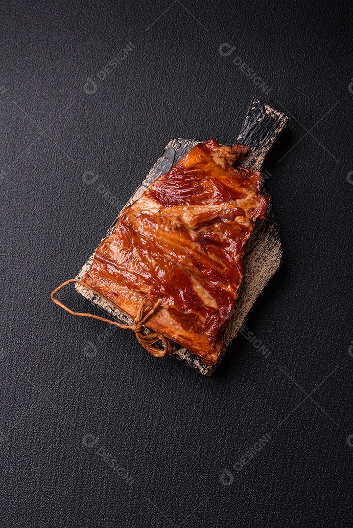 Deliciosas costelas defumadas ou grelhadas com azeitonas, especiarias e ervas sobre fundo escuro de concreto