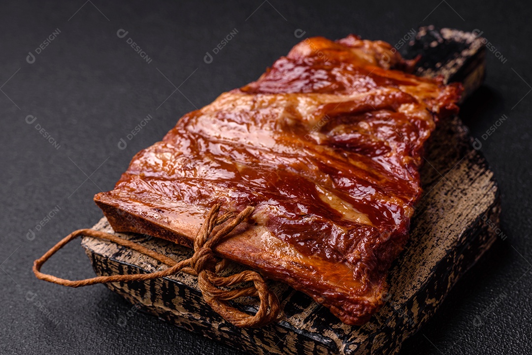 Deliciosas costelas defumadas ou grelhadas com azeitonas, especiarias e ervas sobre fundo escuro de concreto