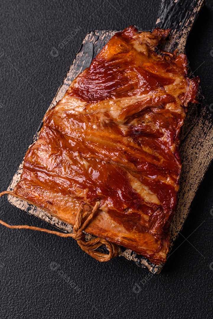 Deliciosas costelas defumadas ou grelhadas com azeitonas, especiarias e ervas sobre fundo escuro de concreto