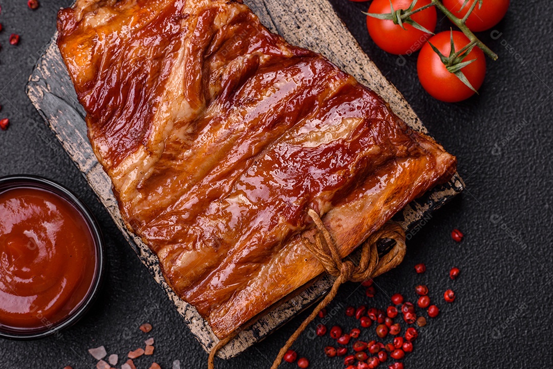 Deliciosas costelas defumadas ou grelhadas com azeitonas, especiarias e ervas sobre fundo escuro de concreto