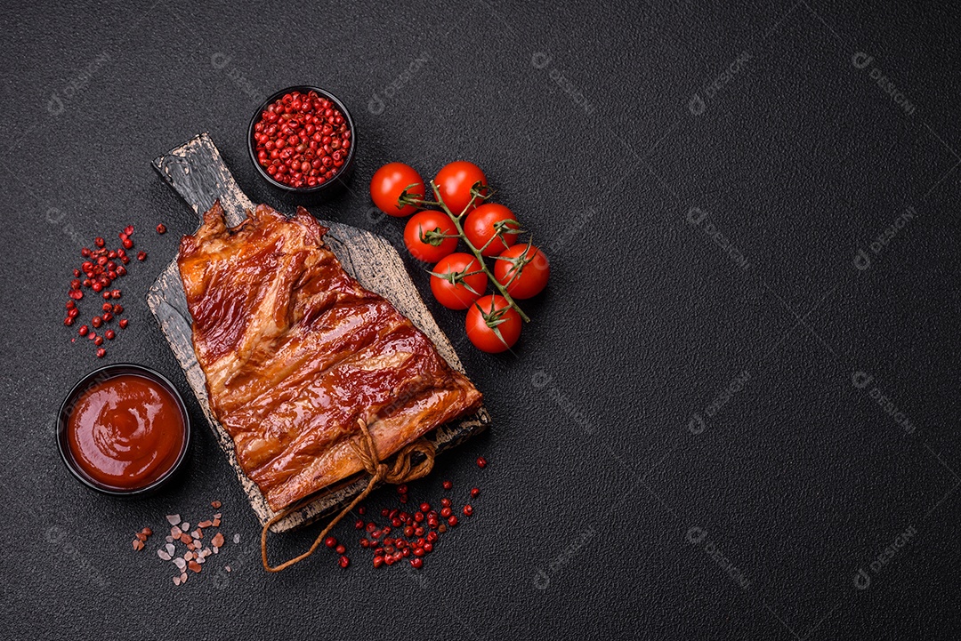 Deliciosas costelas defumadas ou grelhadas com azeitonas, especiarias e ervas sobre fundo escuro de concreto