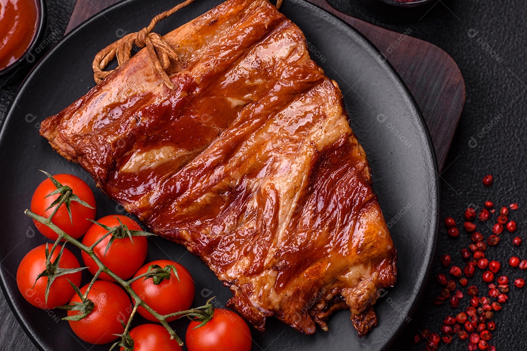 Deliciosas costelas defumadas ou grelhadas com azeitonas, especiarias e ervas sobre fundo escuro de concreto