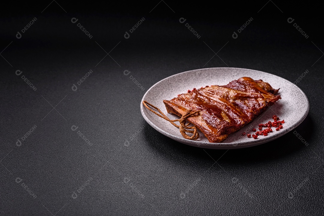 Deliciosas costelas defumadas ou grelhadas com azeitonas, especiarias e ervas sobre fundo escuro de concreto