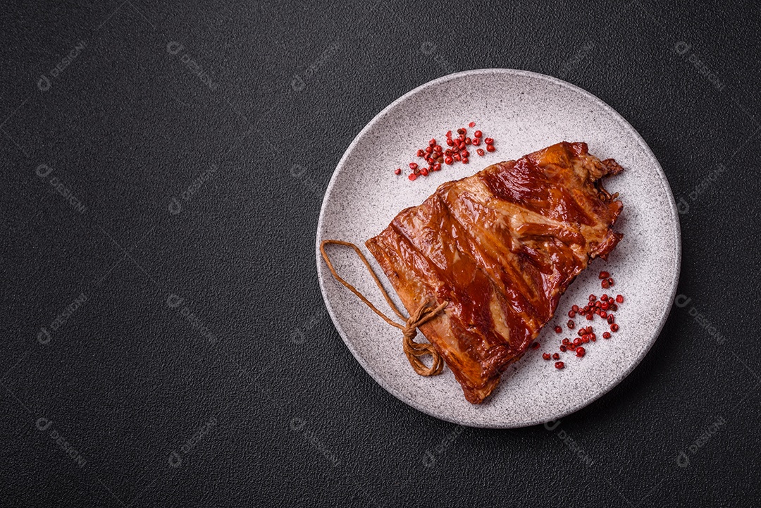 Deliciosas costelas defumadas ou grelhadas com azeitonas, especiarias e ervas sobre fundo escuro de concreto