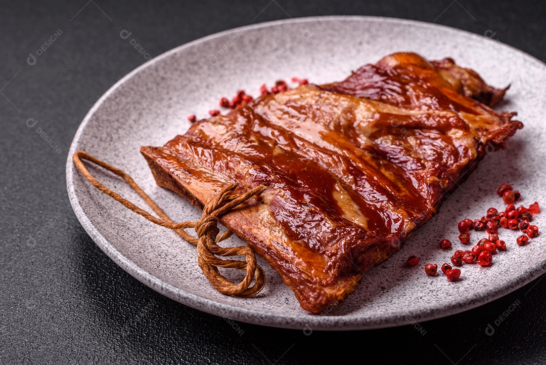 Deliciosas costelas defumadas ou grelhadas com azeitonas, especiarias e ervas sobre fundo escuro de concreto