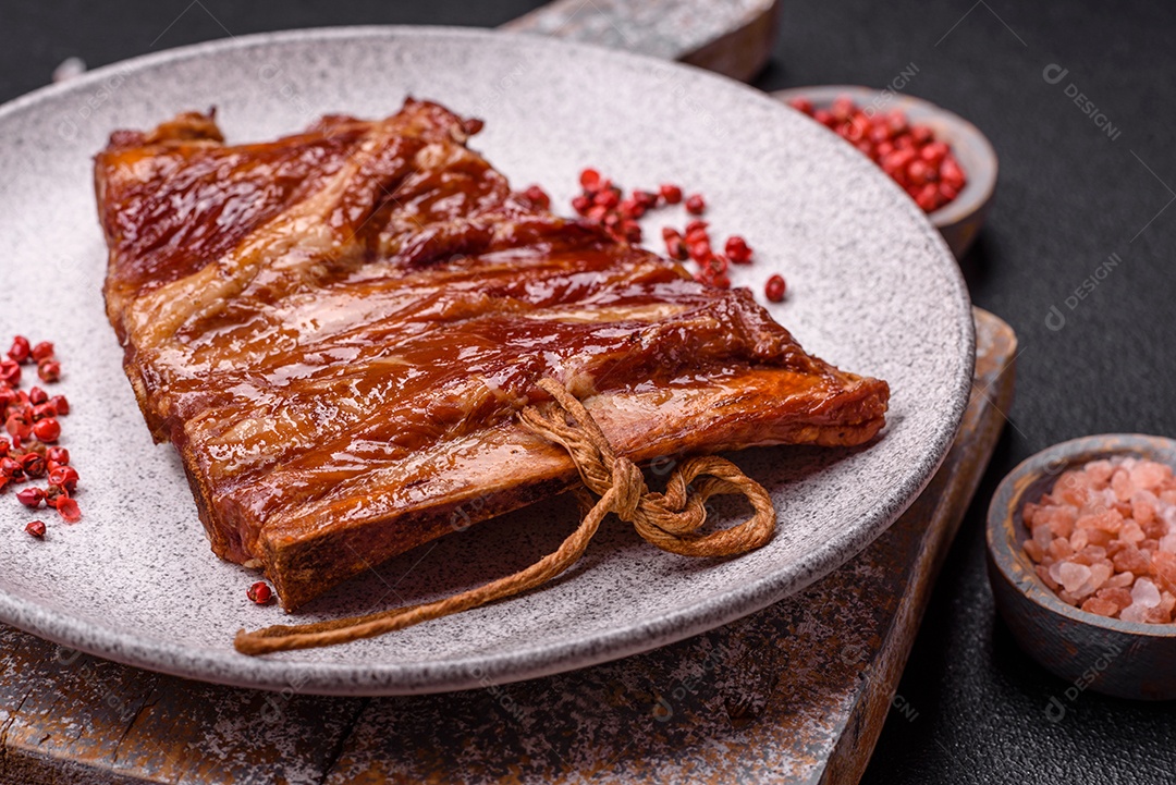 Deliciosas costelas defumadas ou grelhadas com azeitonas, especiarias e ervas sobre fundo escuro de concreto