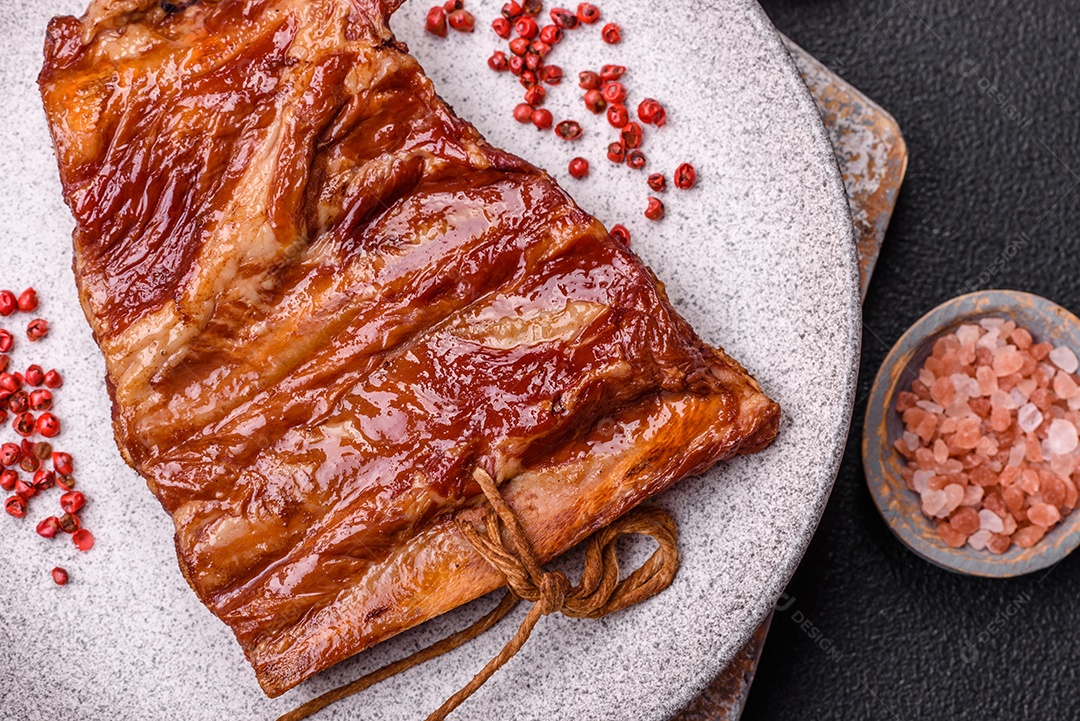 Deliciosas costelas defumadas ou grelhadas com azeitonas, especiarias e ervas sobre fundo escuro de concreto