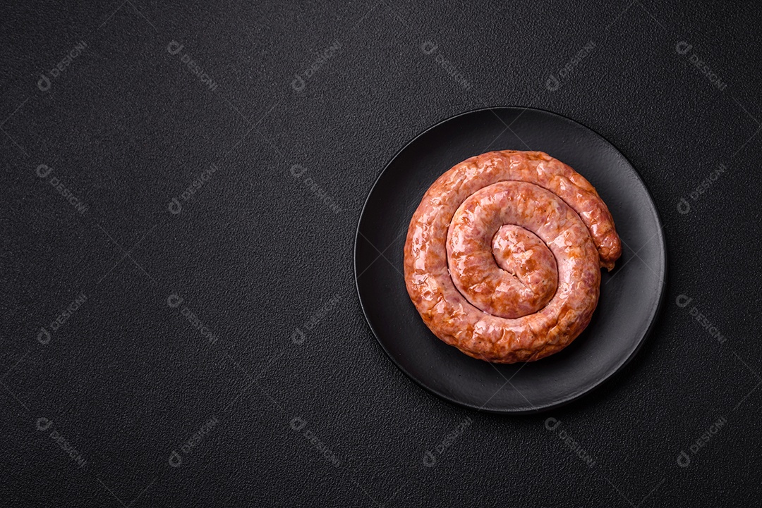 Deliciosa salsicha grelhada em forma de anel com sal, especiarias e ervas sobre fundo escuro de concreto