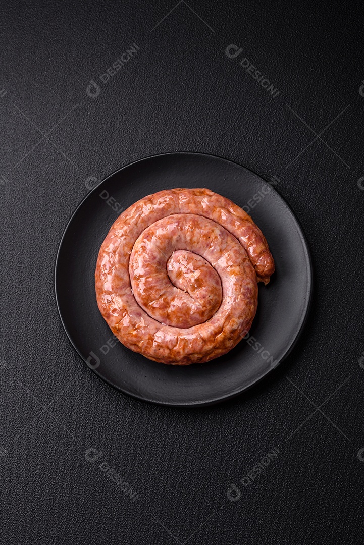 Deliciosa salsicha grelhada em forma de anel com sal, especiarias e ervas sobre fundo escuro de concreto