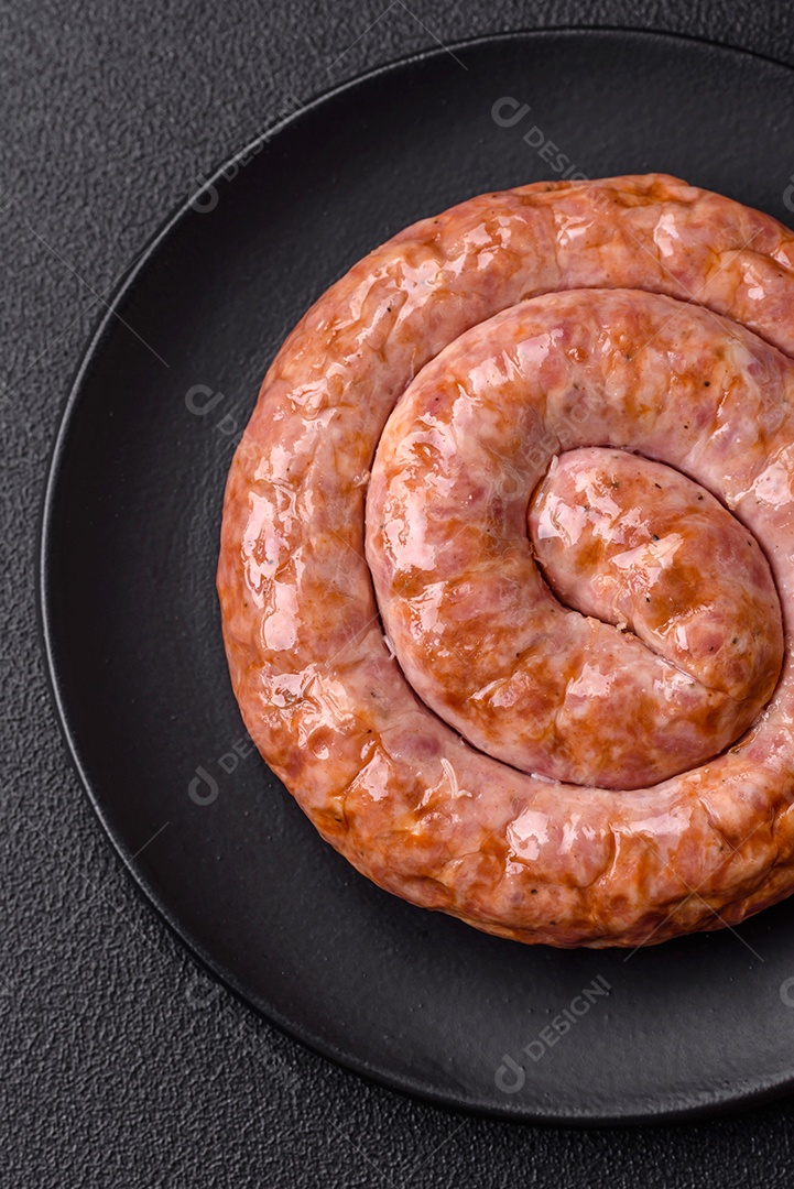 Deliciosa salsicha grelhada em forma de anel com sal, especiarias e ervas sobre fundo escuro de concreto