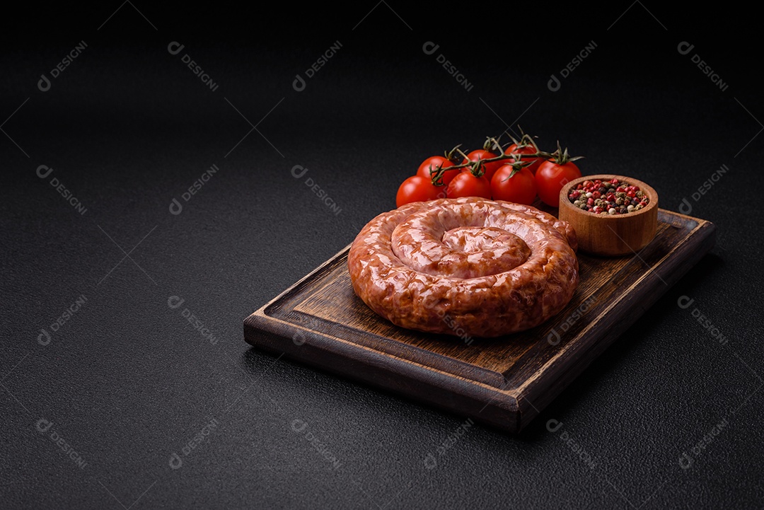 Deliciosa salsicha grelhada em forma de anel com sal, especiarias e ervas sobre fundo escuro de concreto
