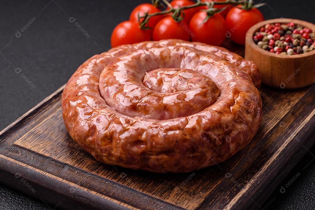 Deliciosa salsicha grelhada em forma de anel com sal, especiarias e ervas sobre fundo escuro de concreto