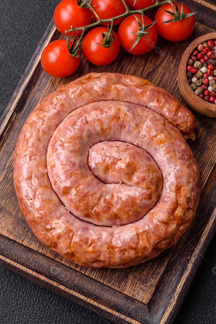 Deliciosa salsicha grelhada em forma de anel com sal, especiarias e ervas sobre fundo escuro de concreto