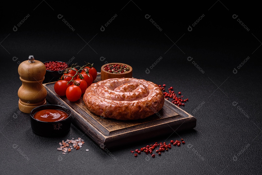 Deliciosa salsicha grelhada em forma de anel com sal, especiarias e ervas sobre fundo escuro de concreto