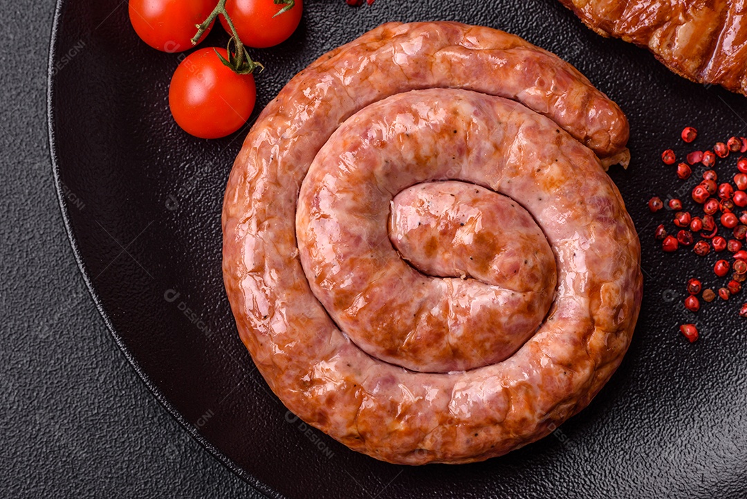 Deliciosa salsicha grelhada em forma de anel com sal, especiarias e ervas sobre fundo escuro de concreto