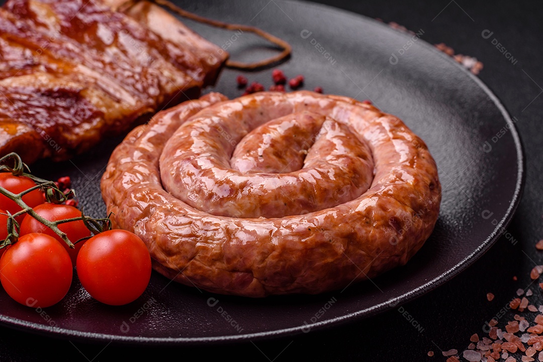 Deliciosa salsicha grelhada em forma de anel com sal, especiarias e ervas sobre fundo escuro de concreto