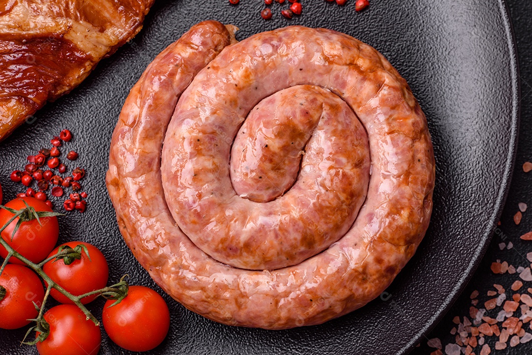Deliciosa salsicha grelhada em forma de anel com sal, especiarias e ervas sobre fundo escuro de concreto