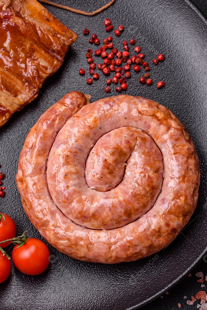 Deliciosa salsicha grelhada em forma de anel com sal, especiarias e ervas sobre fundo escuro de concreto