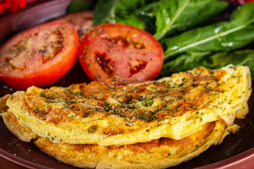 Prato com omelete e salada de tomate fatiado e rúcula