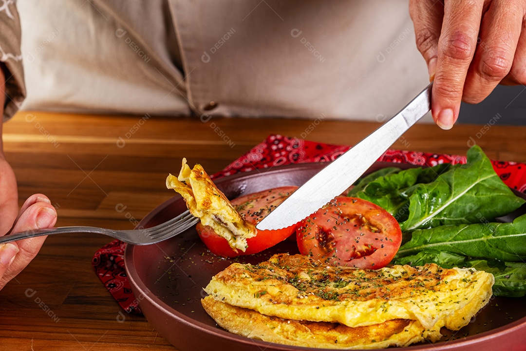 Prato com omelete e salada de tomate fatiado e rúcula