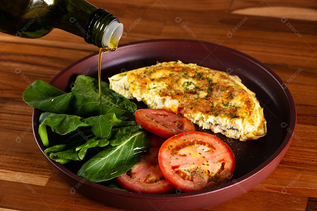 Prato com omelete e salada de tomate fatiado e rúcula