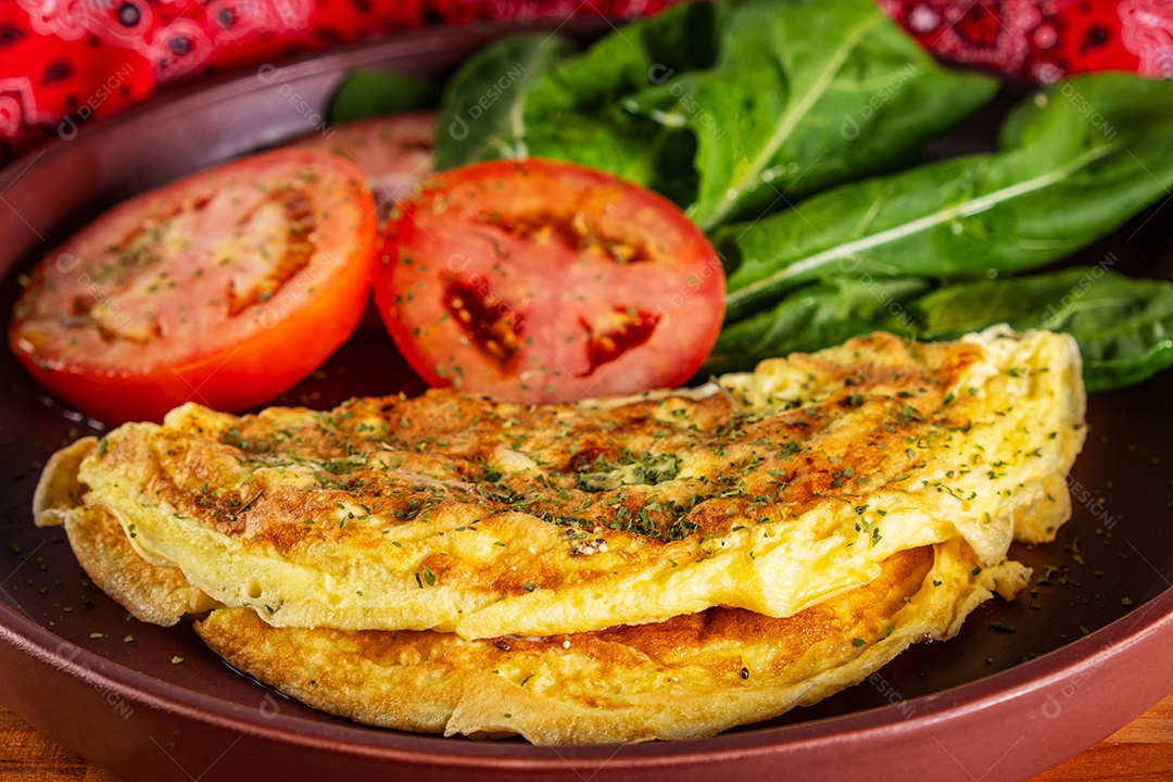 Prato com omelete e salada de tomate fatiado e rúcula