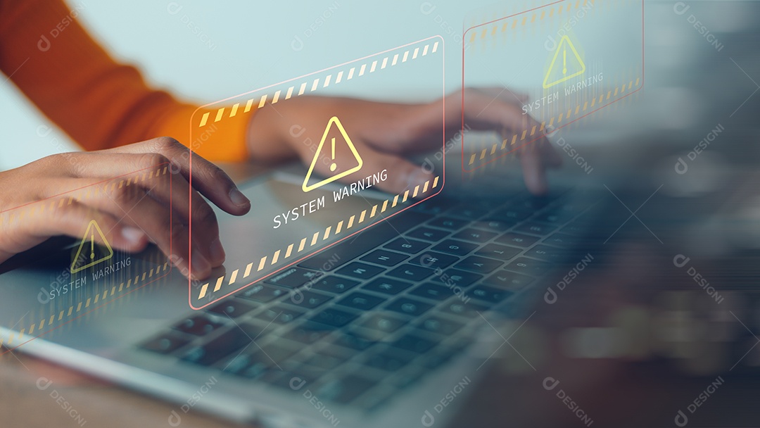 Uma pessoa está digitando em um laptop com um sinal de alerta na tela