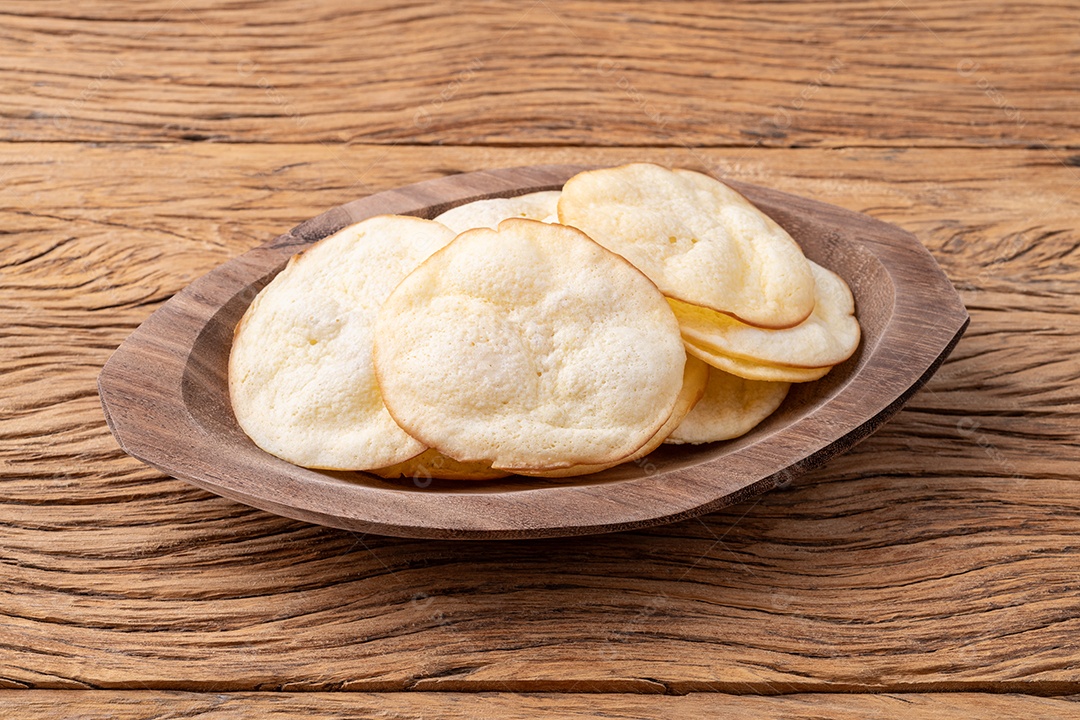 Lascas de queijo provolone defumado em uma tigela sobre a mesa de madeira