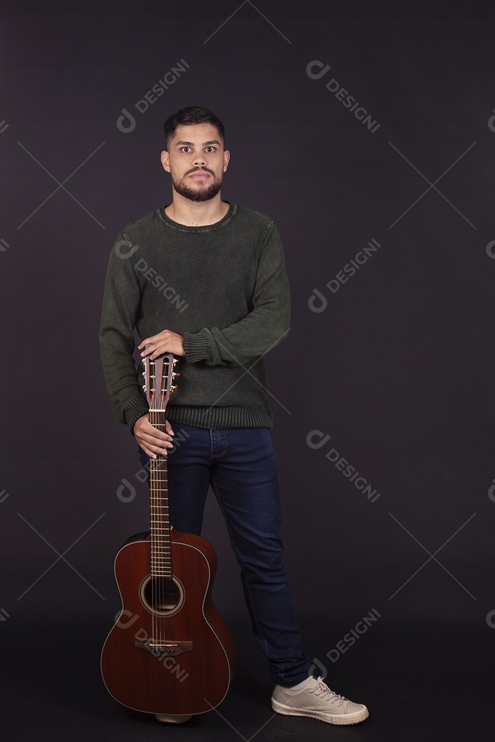 Homem jovem ao lado de violão sobre fundo isolado