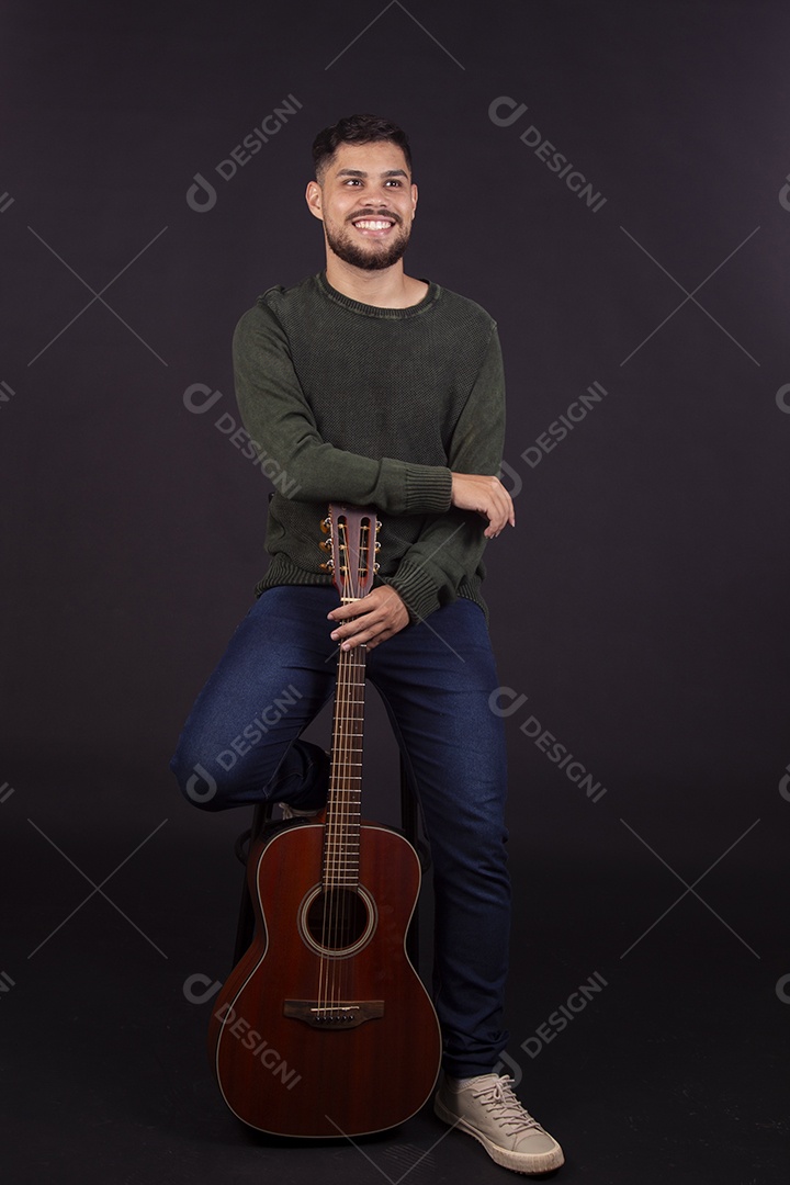 Homem jovem ao lado de violão sobre fundo isolado