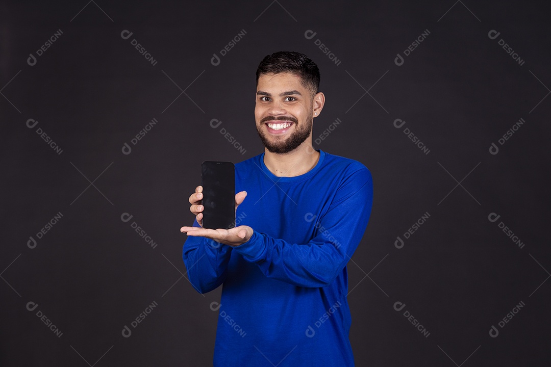 Homem jovem garoto barbudo sobre fundo isolado segurando celular smartphone