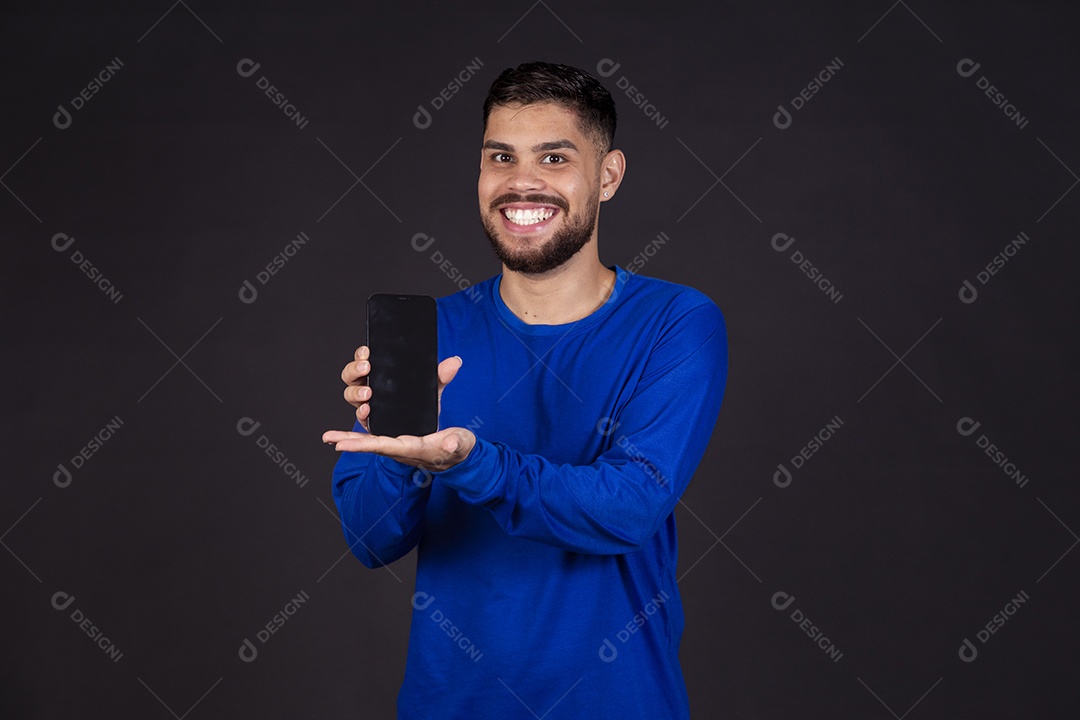 Homem jovem garoto barbudo sobre fundo isolado segurando celular smartphone