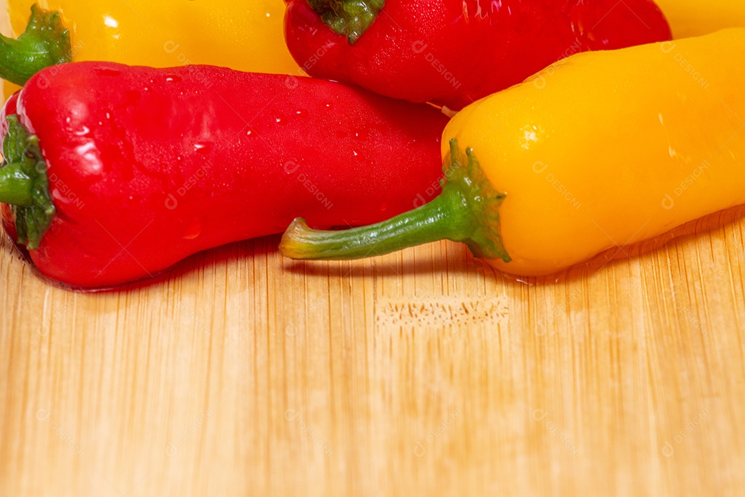 Pimentões amarelos e vermelhos na mesa de madeira