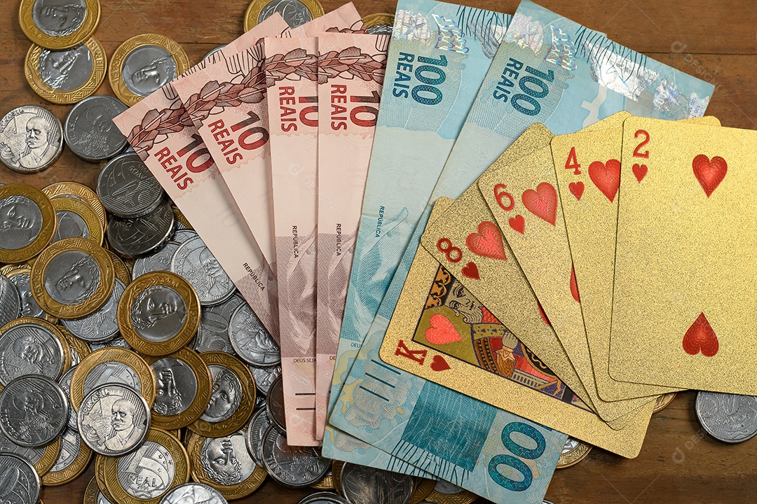 Várias moedas notas de dinheiro e cartas de baralho