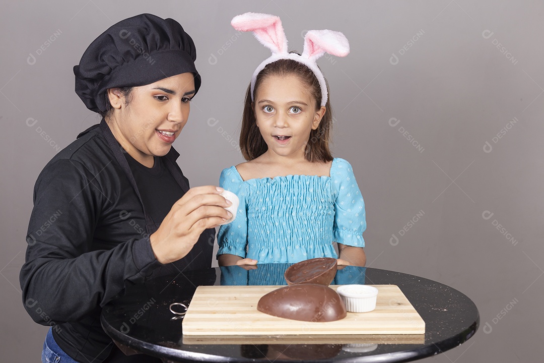 Mãe ao lado de sua filha comendo ovos de páscoa