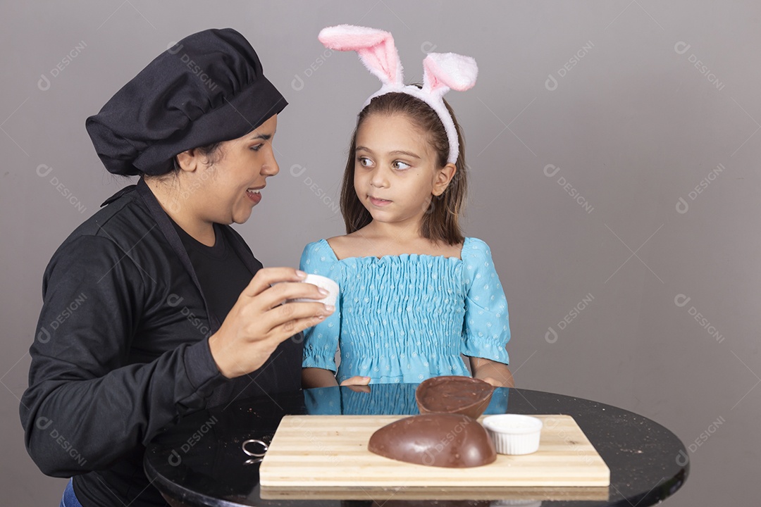 Mãe ao lado de sua filha comendo ovos de páscoa