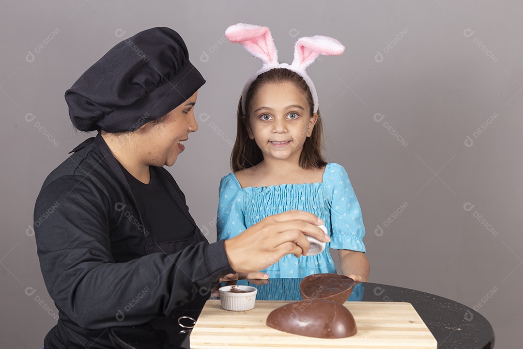 Mãe ao lado de sua filha comendo ovos de páscoa