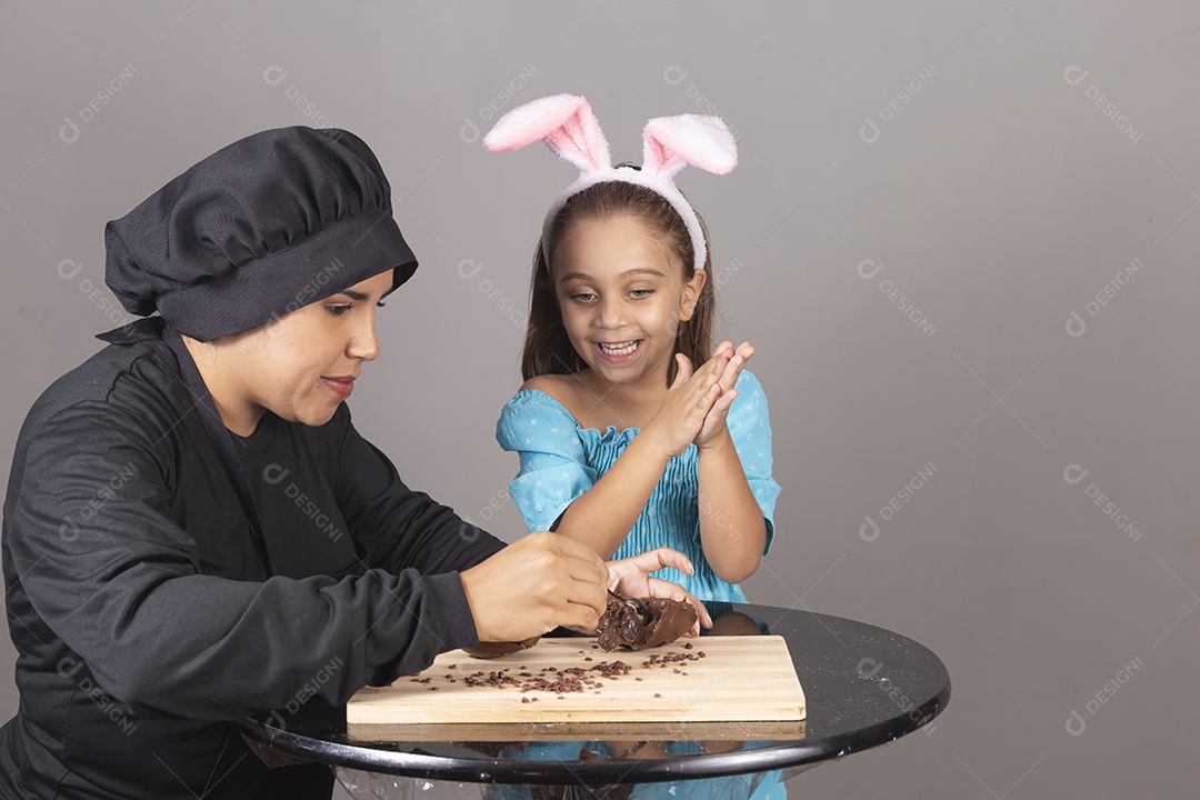 Mãe ao lado de sua filha comendo ovos de páscoa