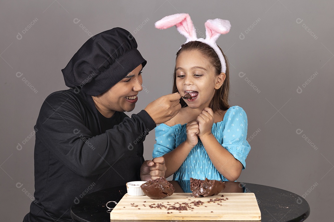 Mãe ao lado de sua filha comendo ovos de páscoa