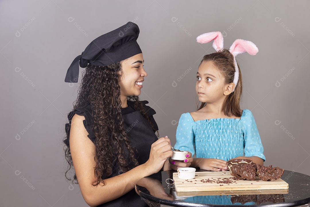 Mãe ao lado de sua filha comendo ovos de páscoa