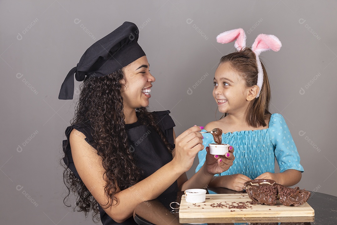 Mãe ao lado de sua filha comendo ovos de páscoa