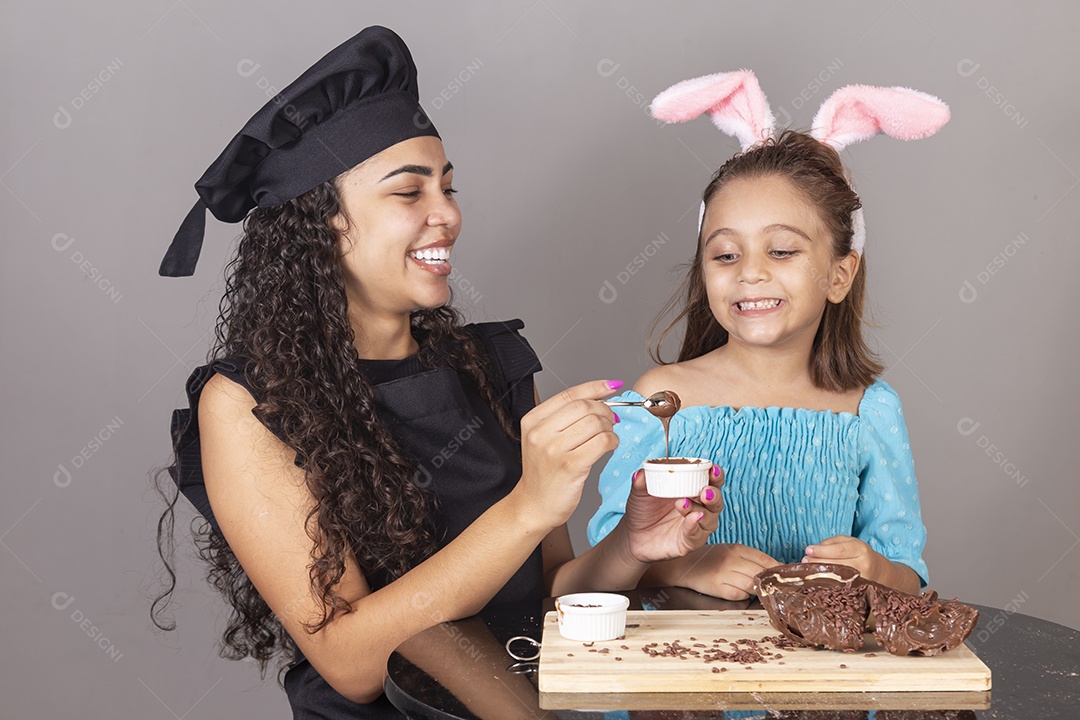 Mãe ao lado de sua filha comendo ovos de páscoa