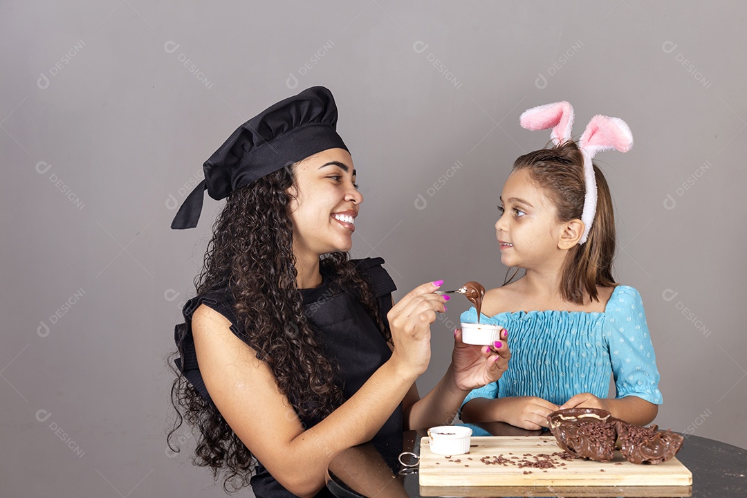 Mãe ao lado de sua filha comendo ovos de páscoa