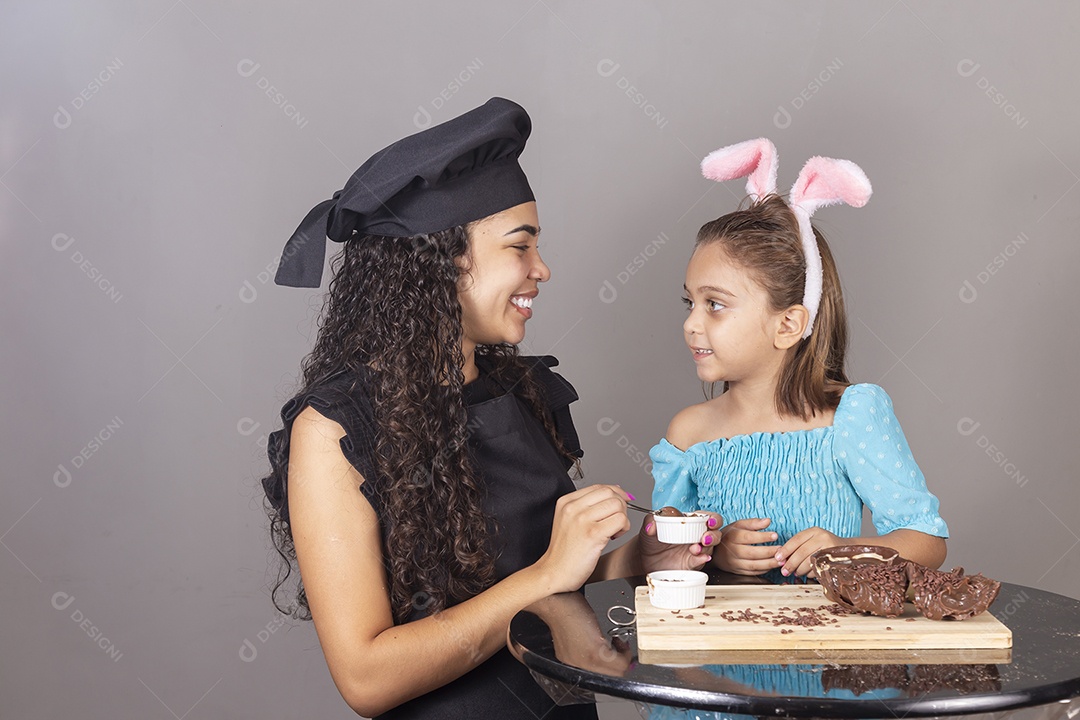 Mãe ao lado de sua filha comendo ovos de páscoa