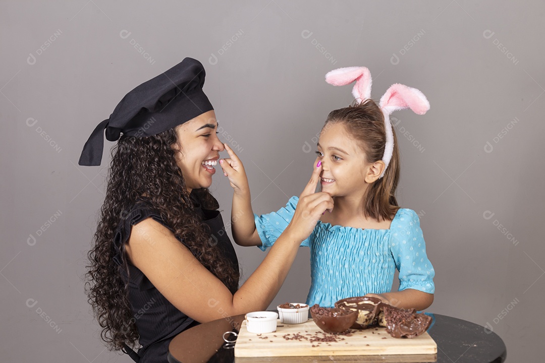 Mãe ao lado de sua filha comendo ovos de páscoa